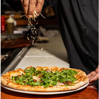 Chef putting cheese on a pizza.